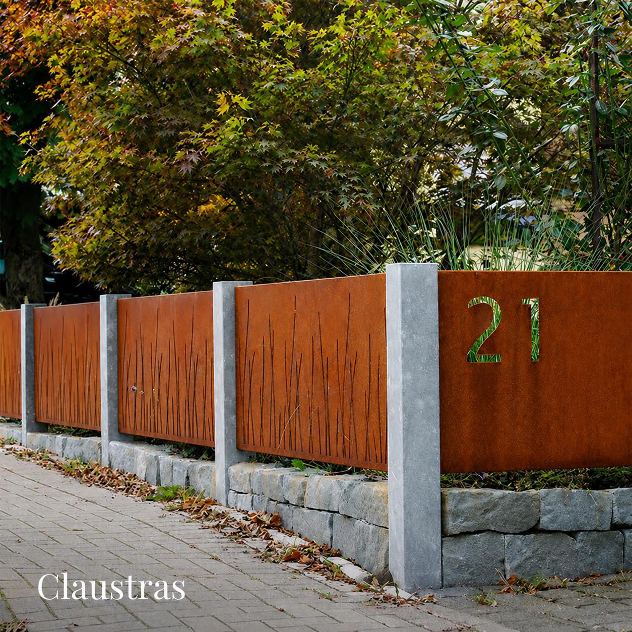 Clôture paysagère en acier Corten composée de panneaux décoratifs intégrés entre des poteaux en pierre.