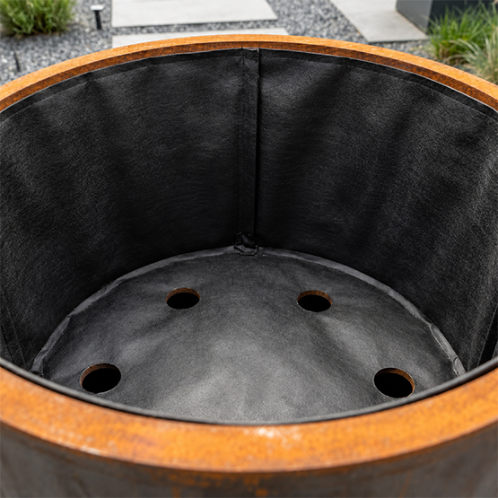 Détail du système de drainage intégré au fond d’une jardinière en acier Corten sur mesure.