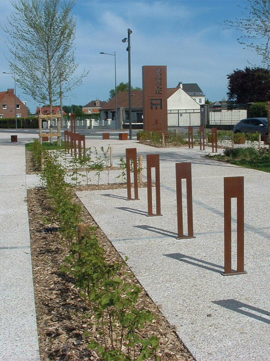 Alignement de bornes verticales et d’un élément de signalétique en acier Corten dans un aménagement urbain paysager.