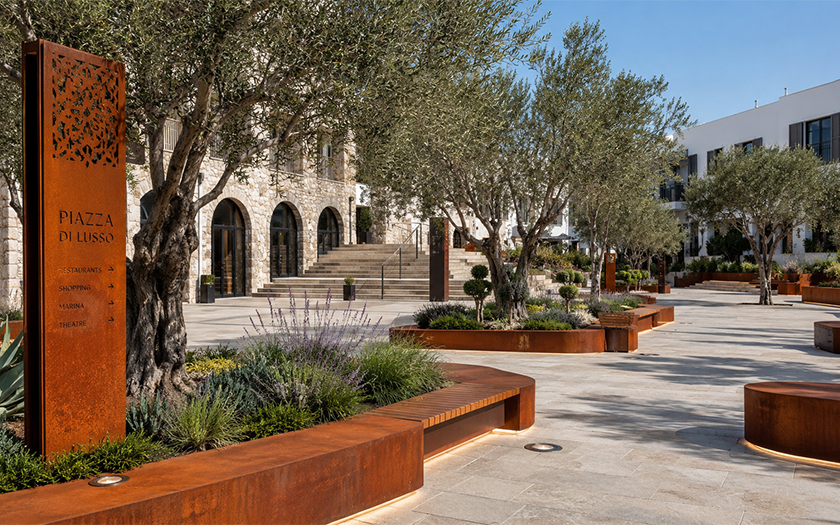 Place publique aménagée avec un totem de signalétique, des bancs et des jardinières en acier Corten.