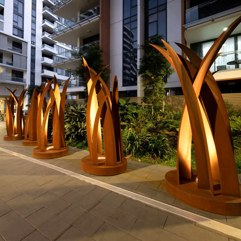 Ensemble de sculptures lumineuses en acier Corten installé le long d’un chemin paysager dans une résidence contemporaine.